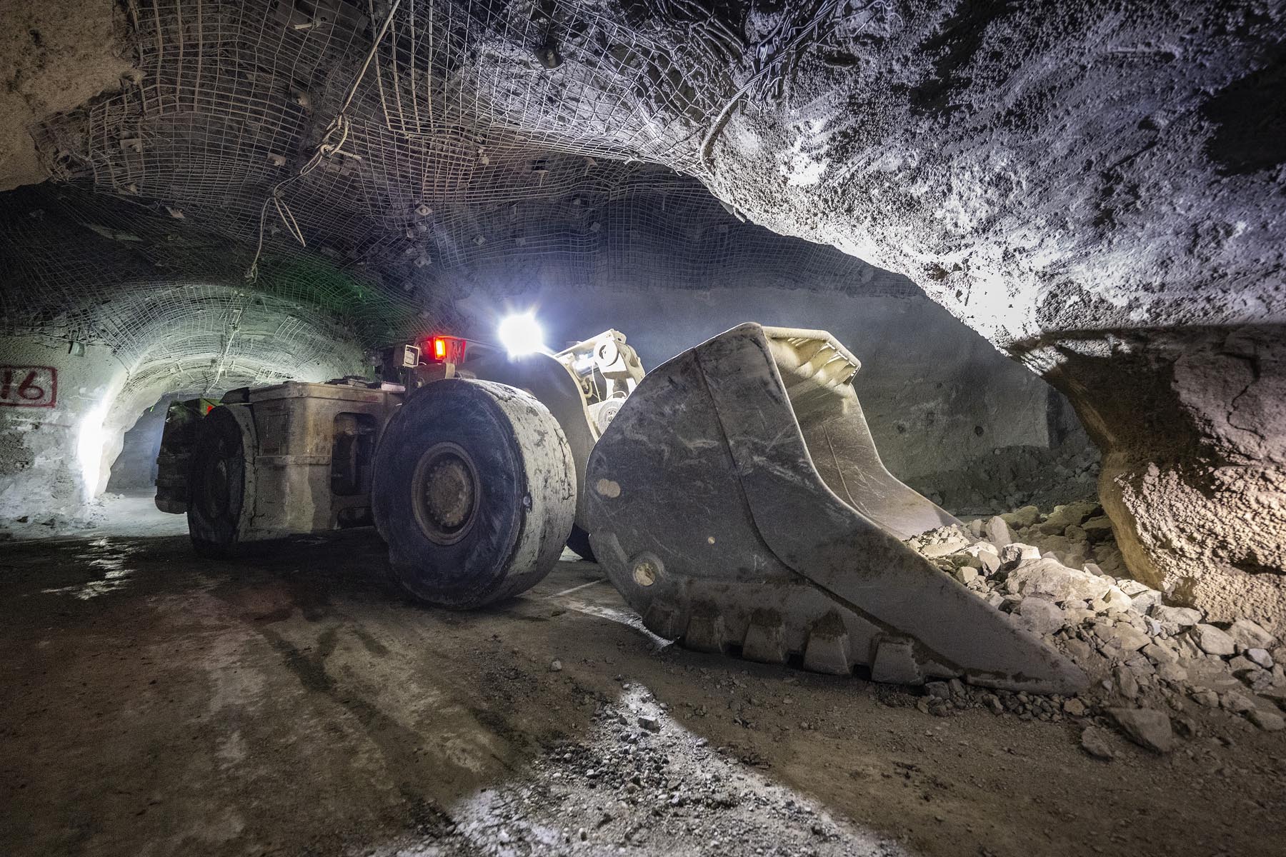 Underground mine tunnel with WiFi access points, RFID tag readers on equipment, and a central dispatch screen showing real-time vehicle positions